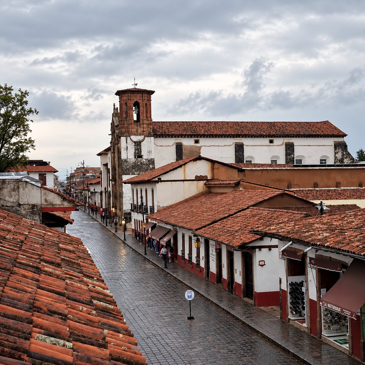 Vista de la calle Padre Manuel de la Torre Lloreda en Pátzcuaro, con piso mojado, casas coloniales de teja y, al fondo, el conjunto de la Compañía de Jesús.